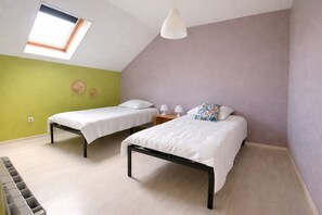 Ein Zimmer mit zwei Betten, einem Oberlicht und einer Pendelleuchte.