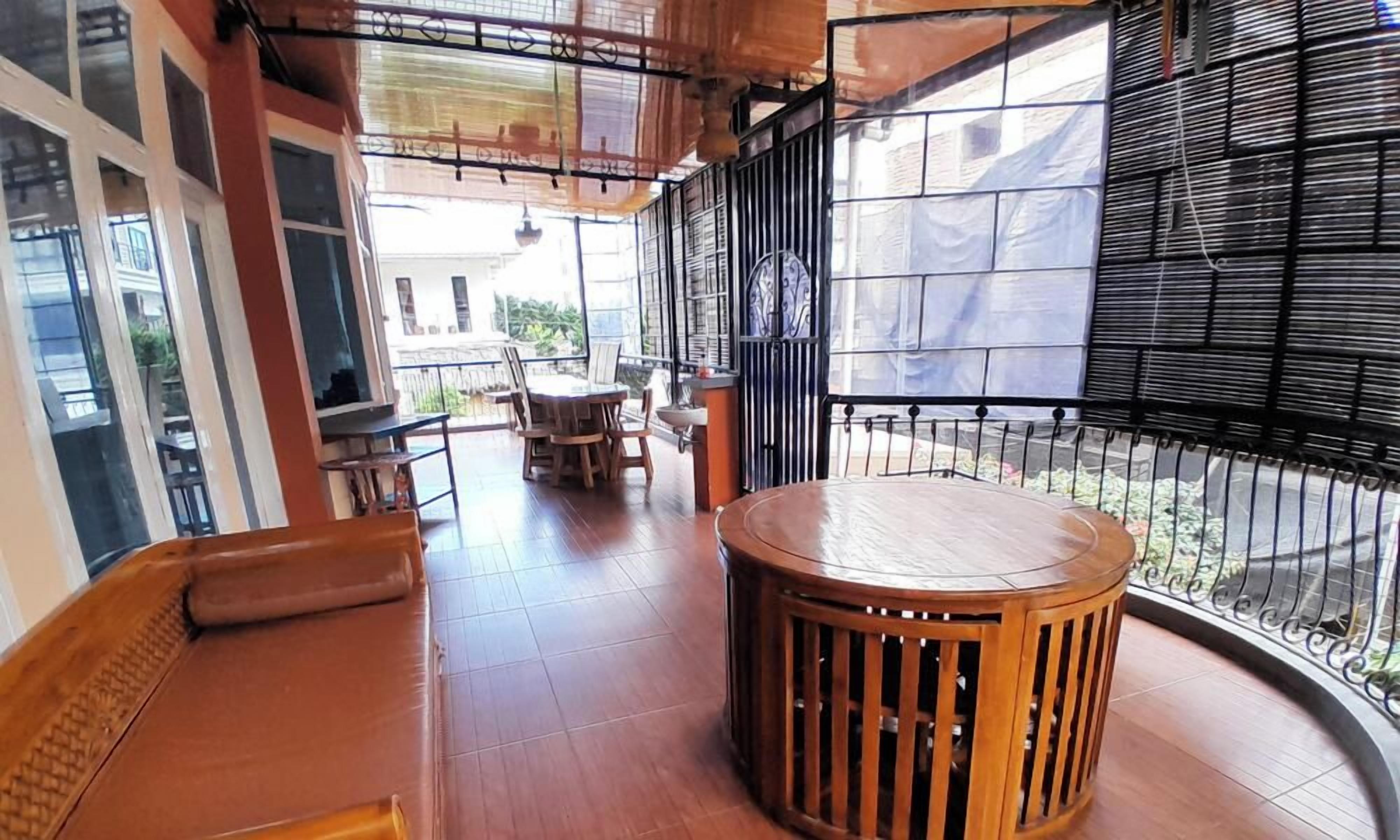 A balcony with a wooden table and chairs, a cushioned bench, and a view of a courtyard.