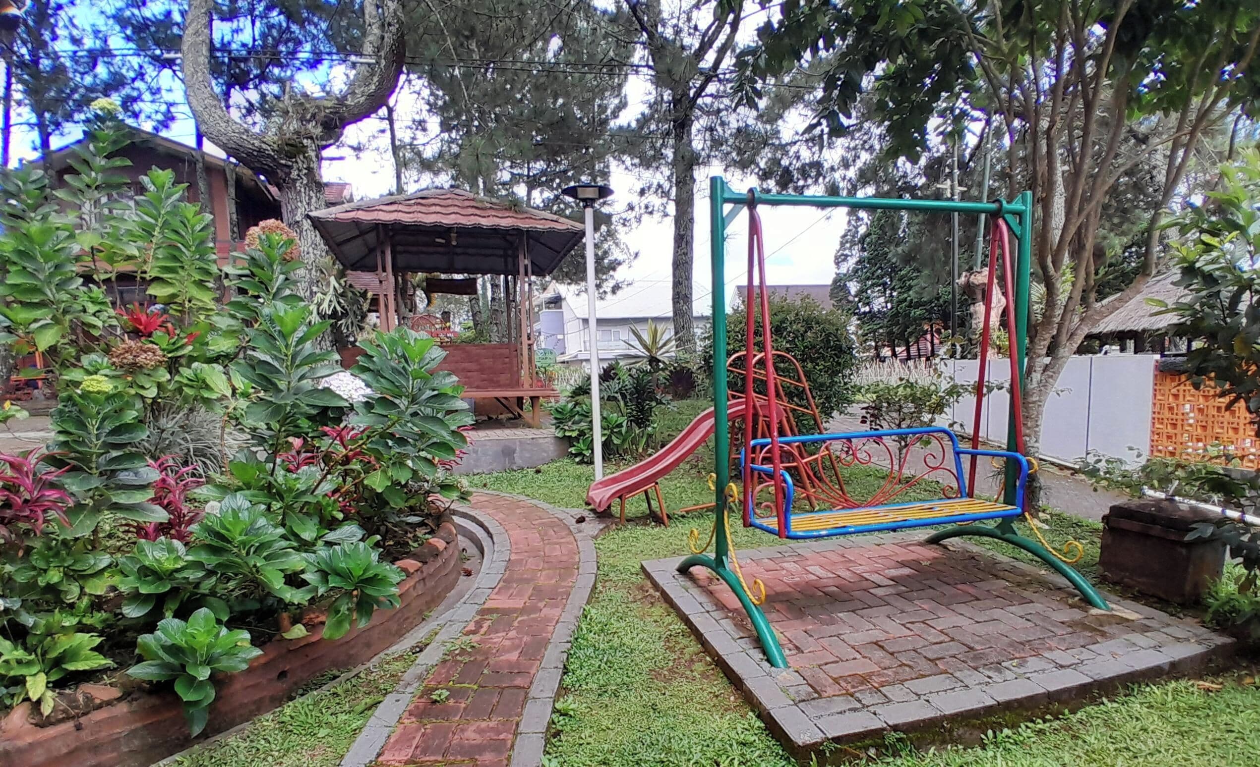 Un parque infantil con columpios, tobogán y una zona de estar cubierta.