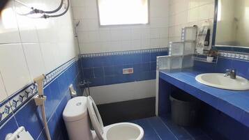Un baño con inodoro, bidé, lavabo y espejo.