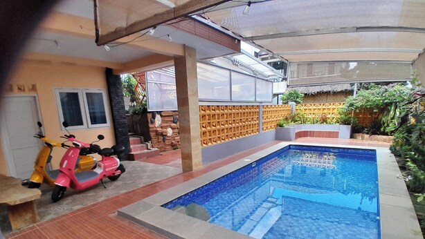 A swimming pool with a tiled edge, a pink scooter, and a covered patio area. - Villa Dinar Mountain Estate  (Bandung Barat)