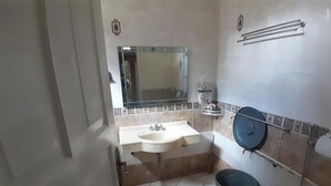 A bathroom with a sink, mirror, towel rack, and a trash bin. - Villa Dinar Mountain Estate  (Bandung Barat)