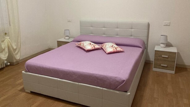 A bed with a headboard, two bedside tables, and a lamp on each side.