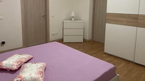 A bedroom with a bed, a nightstand, a wardrobe, and a door.