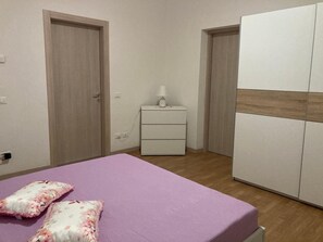 A bedroom with a bed, a nightstand, a wardrobe, and a door. - Room 'Double  with Private Bathroom' with Shared Garden, Wi-Fi and Air Conditioning (Monzambano)