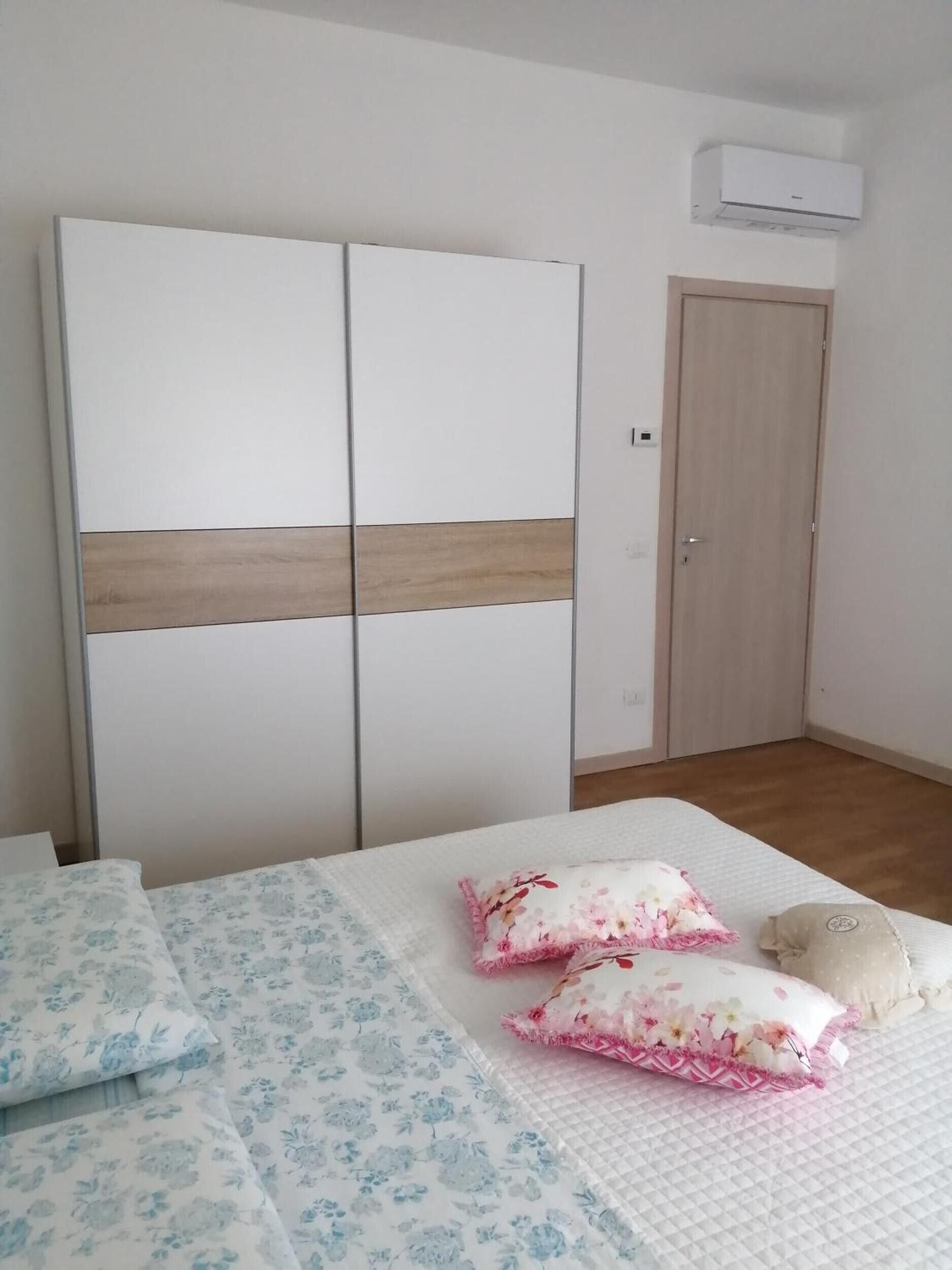 Ein Schlafzimmer mit einem Bett, zwei Kissen, einem Schrank und einer Tür.