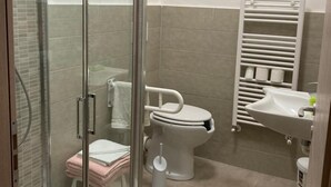 A bathroom with a glass-enclosed shower, a toilet, a sink, and a towel rack.