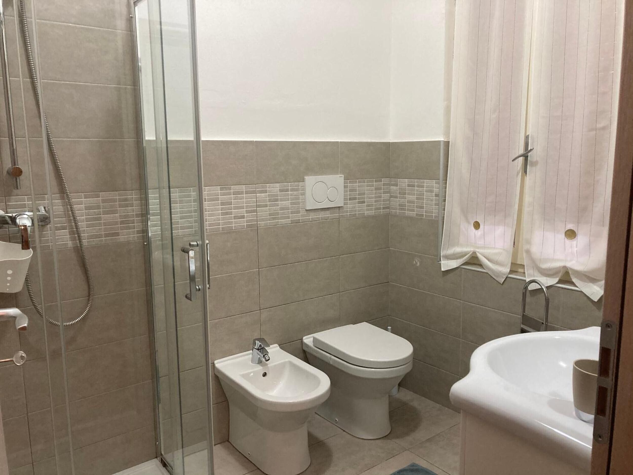 Ein Badezimmer mit einer Duschkabine, einem Bidet, einer Toilette und einem Waschbecken.