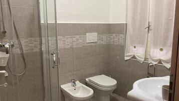 Ein Badezimmer mit einer Duschkabine, einem Bidet, einer Toilette und einem Waschbecken.