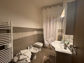 Ein Badezimmer mit Toilette, Bidet, Handtuchhalter und Waschbecken mit Spiegel.