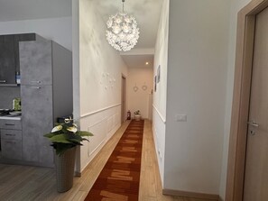 Un pasillo con piso de madera, una lámpara colgante y una planta en maceta.