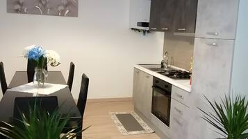 Una cucina moderna con un tavolo da pranzo, sedie, una lampada a sospensione e piante in vaso.