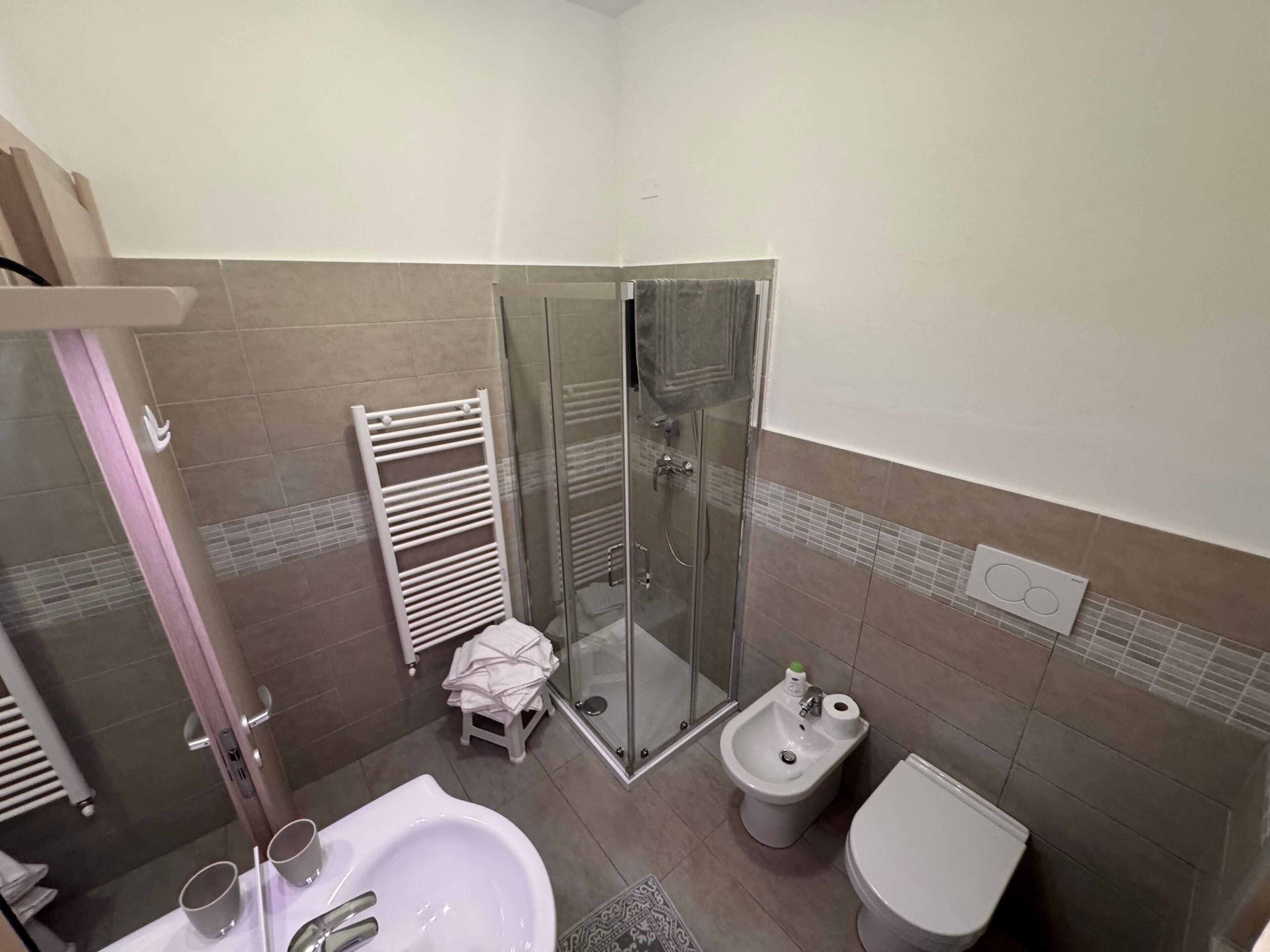 Een badkamer met douche, toilet, wastafel en spiegel.