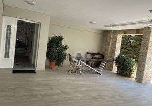 Ein geräumiges Wohnzimmer mit einem Klavier, einem Esstisch mit Stühlen und zwei Zimmerpflanzen.