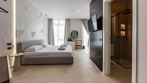 Una habitación de hotel moderna con una cama grande, televisión, escritorio y vestidor.
