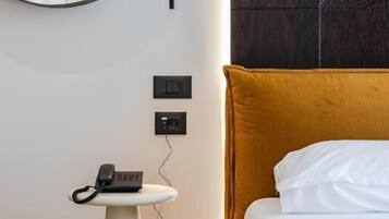 Ein Hotelzimmer mit einem Bett, einem runden Spiegel, einem kleinen Tisch mit Telefon und einer Wandleuchte.