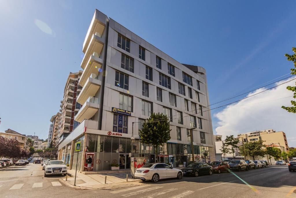 A multi-story hotel with a modern facade, a visible restaurant, and a parking area.