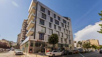 A multi-story hotel with a modern facade, a visible restaurant, and a parking area.
