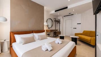 A modern hotel room with a large bed, a sofa, a desk, and a TV.