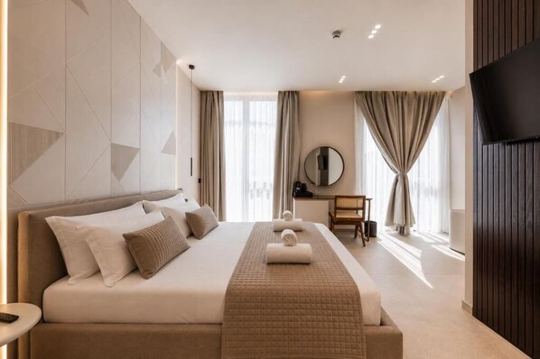 A modern hotel room with a large bed, a desk, a flat-screen TV, and a large window with curtains.