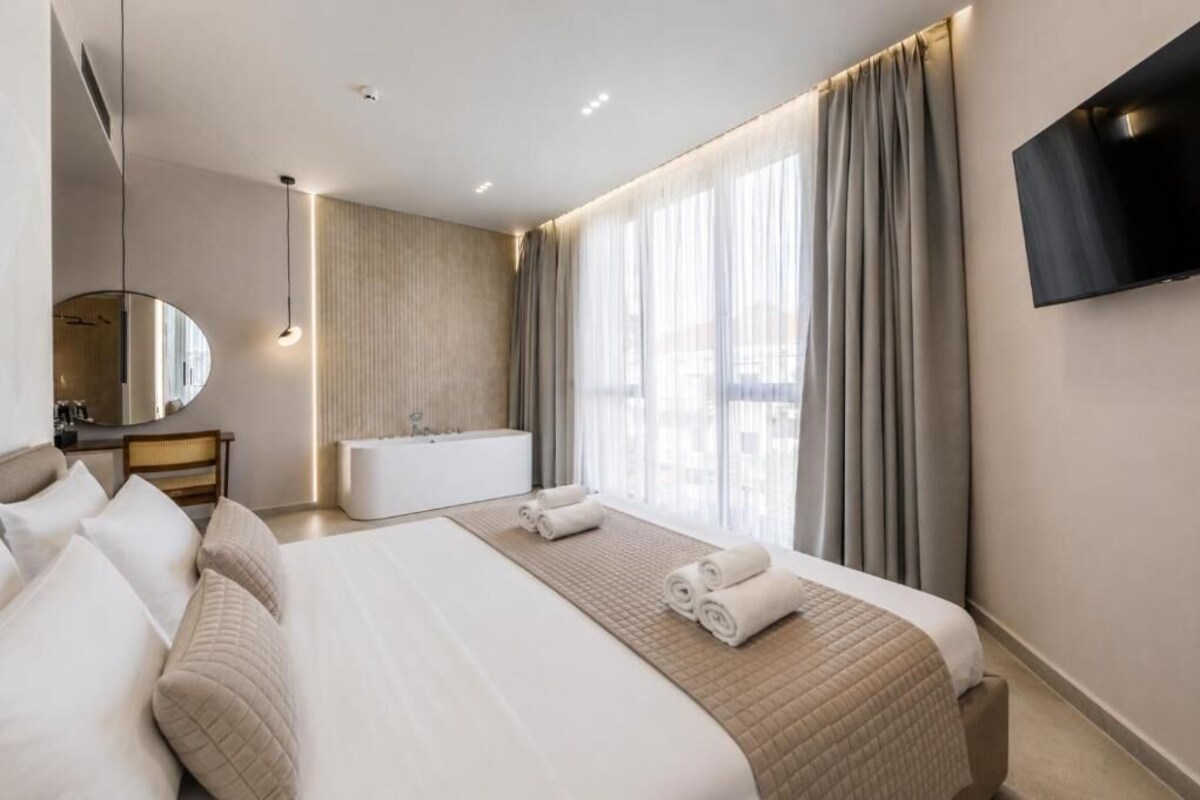 Ein Hotelzimmer mit einem großen Bett, einem Badezimmer und einem an der Wand befestigten Fernseher.