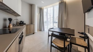 Una cocina moderna con comedor, que incluye una mesa, sillas y un amplio ventanal con cortinas.
