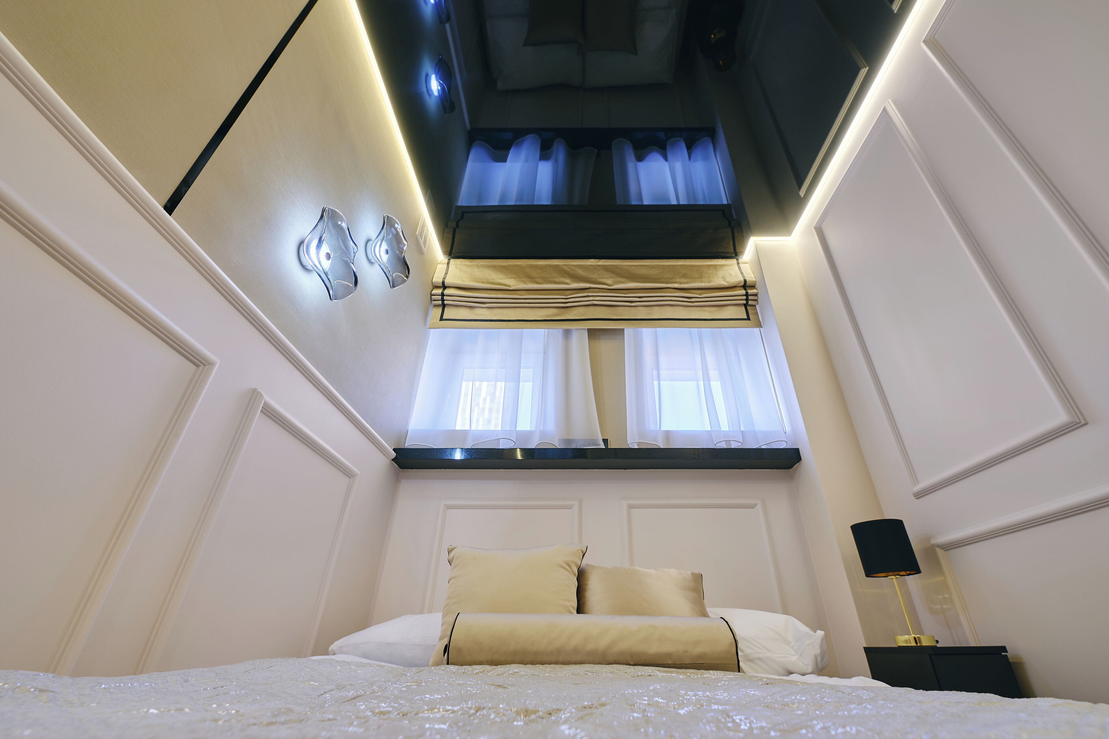 A bedroom with a bed, a nightstand, a lamp, and a window with curtains.