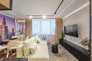 Ein modernes Wohnzimmer mit einer Couch, einem Flachbildfernseher, einem Couchtisch und einer Stadtlandschaftsmalerei an der Wand.