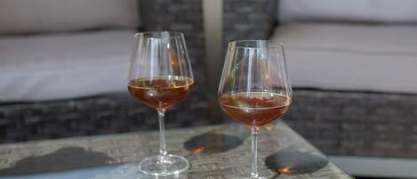 Two wine glasses on a woven table with a sofa in the background.