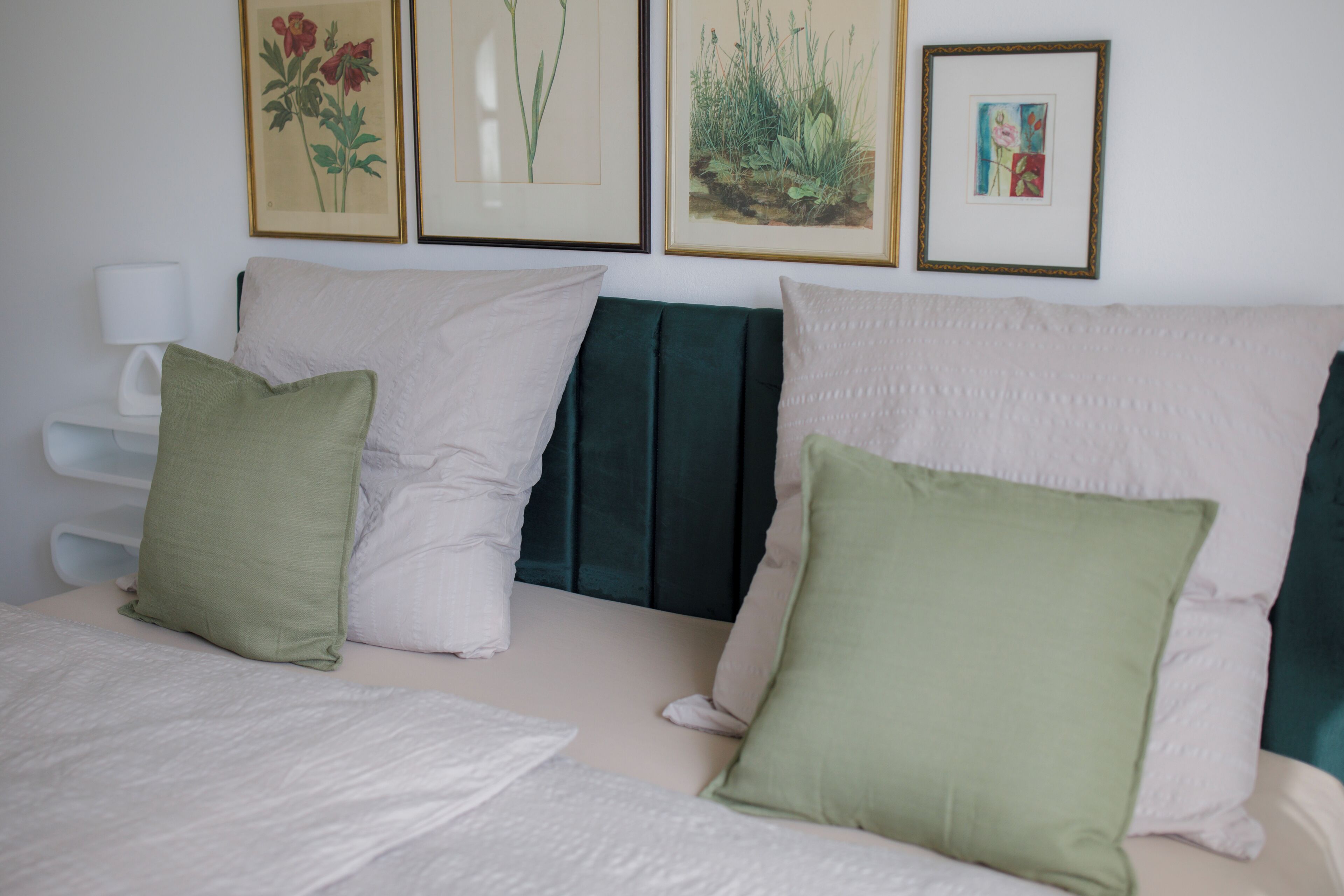 A bed with white bedding and three pillows in different colors.