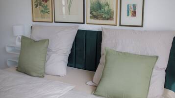 A bed with white bedding and three pillows in different colors.