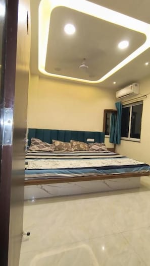 A bedroom with a bed, a ceiling light fixture, and a window with curtains. - Hotel shivansh  (Khandwa)