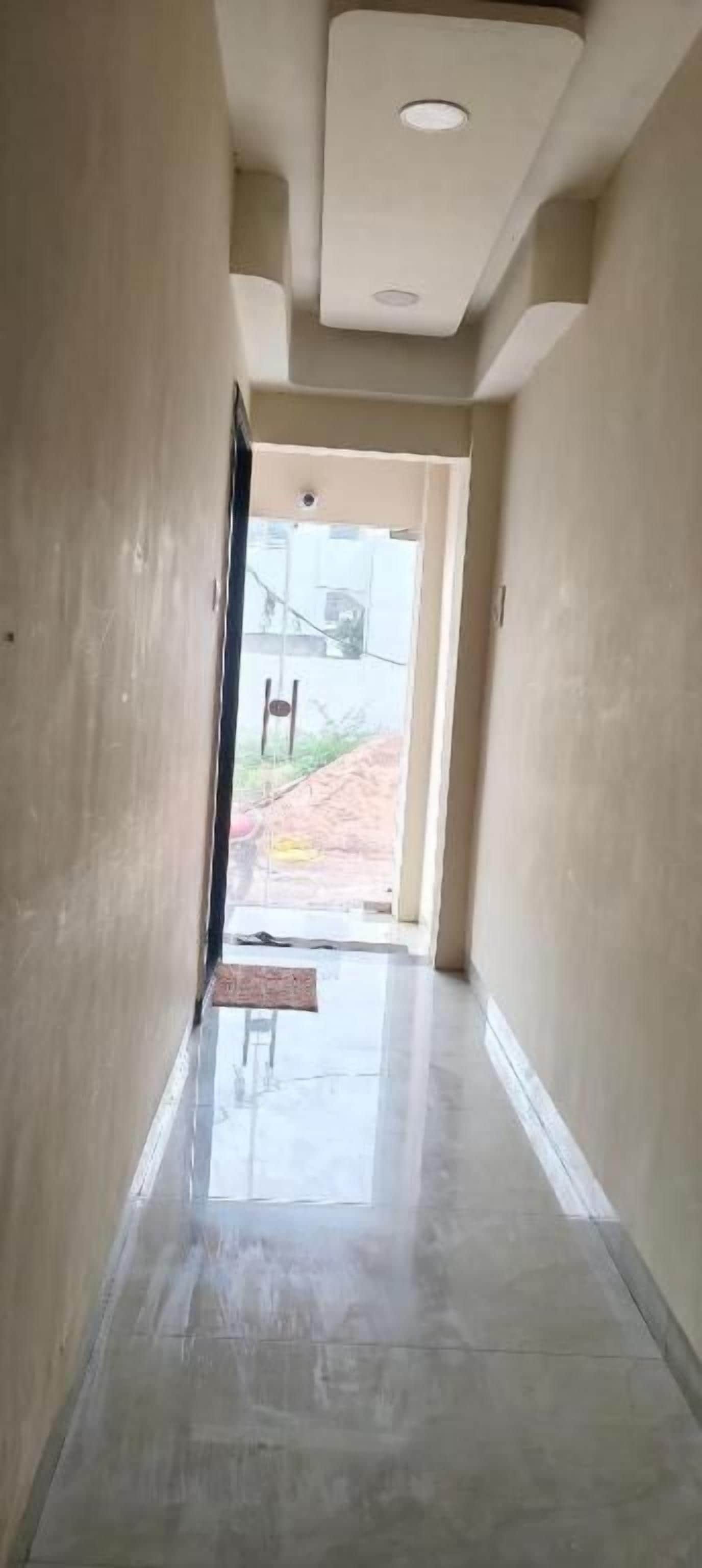 A hallway with a tiled floor leading to an open doorway.