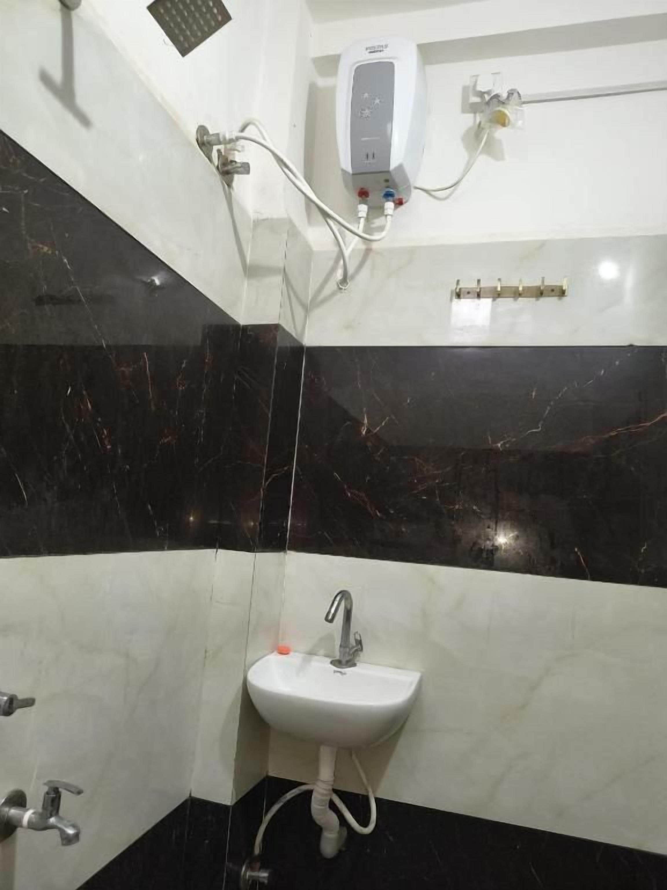 Un baño con lavamanos blanco, paredes de mármol negro y ducha de mano.