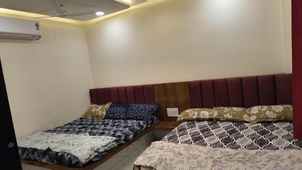 A room with a single bed, a bedside table, and an air conditioning unit on the wall.