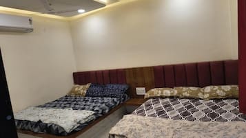 A room with a single bed, a bedside table, and an air conditioning unit on the wall.