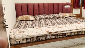 Ein Bett mit Kopfteil, einer Matratze und einer Decke.