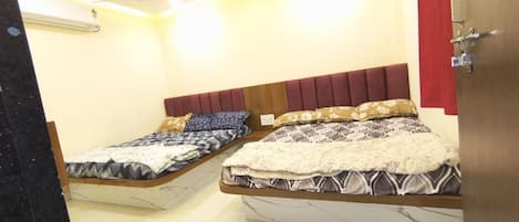 A room with two beds, a wooden headboard, a red curtain, and a marble floor.