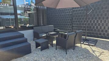 An outdoor patio area with a sofa, table, chairs, and a large umbrella.