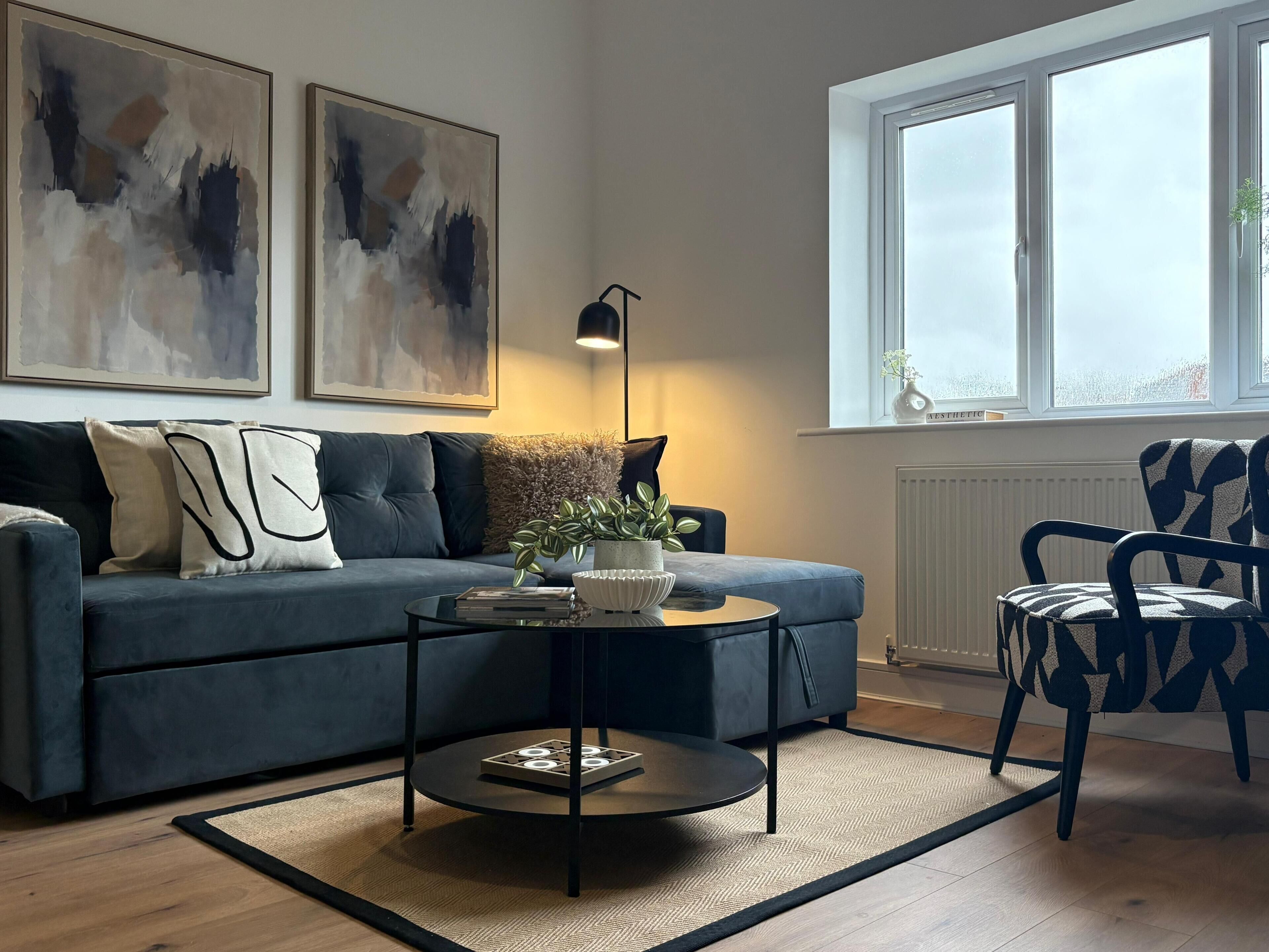 A modern living room with a sofa, a coffee table, and a patterned armchair.