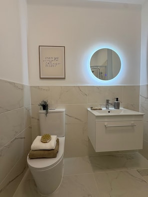 A modern bathroom with a toilet, sink, and a framed inspirational quote on the wall. - 2-Bed, 2-Bath Near Birkdale Golf Club - Flat 5 (Southport)