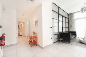 A modern hotel room with a large window, a sofa, and a small table. - Bright & Stylish 2BR Retreat | Socio Dubai Hills (Dubai)