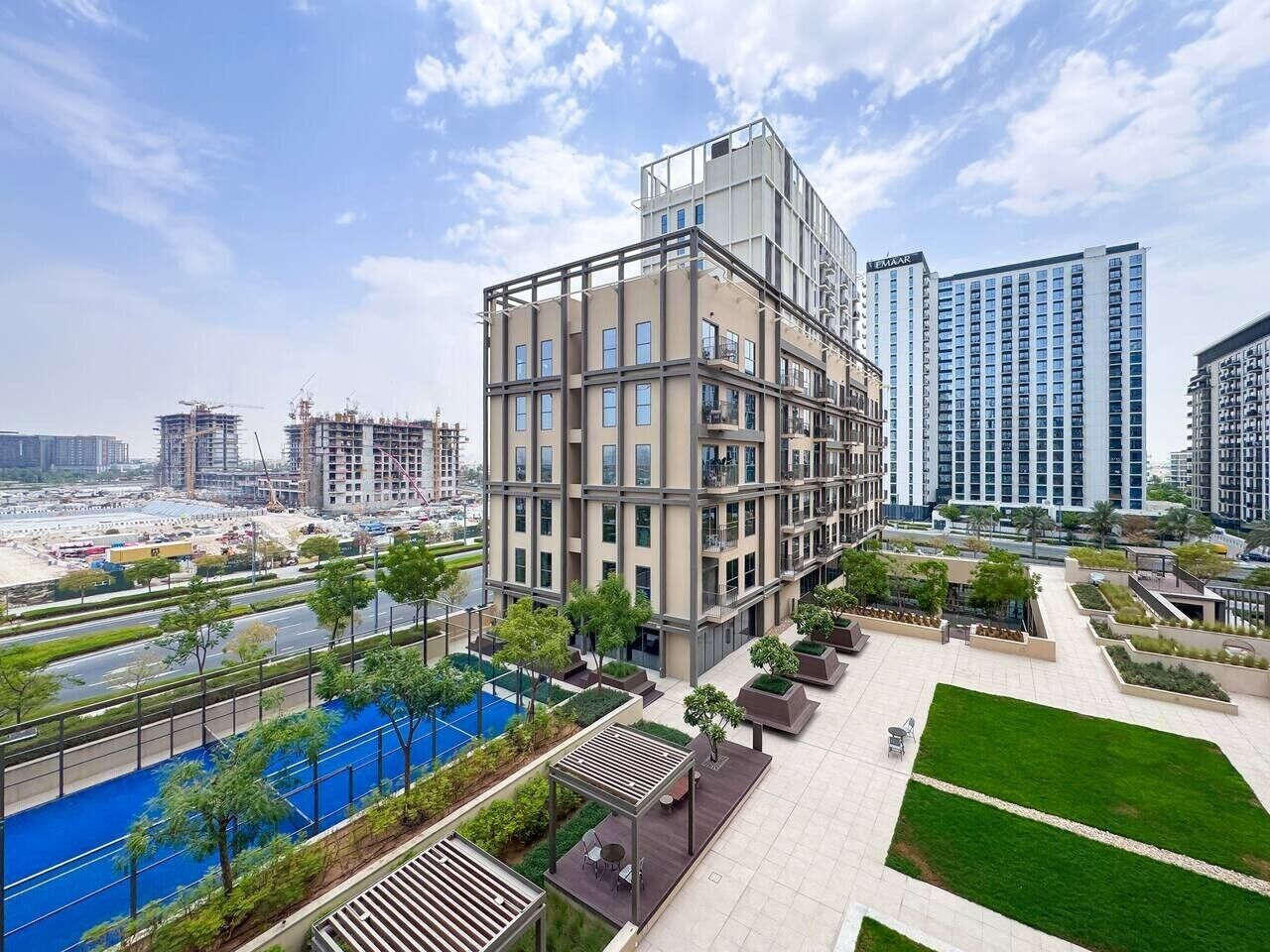 A modern multi-story building with a rooftop pool and landscaped terraces.