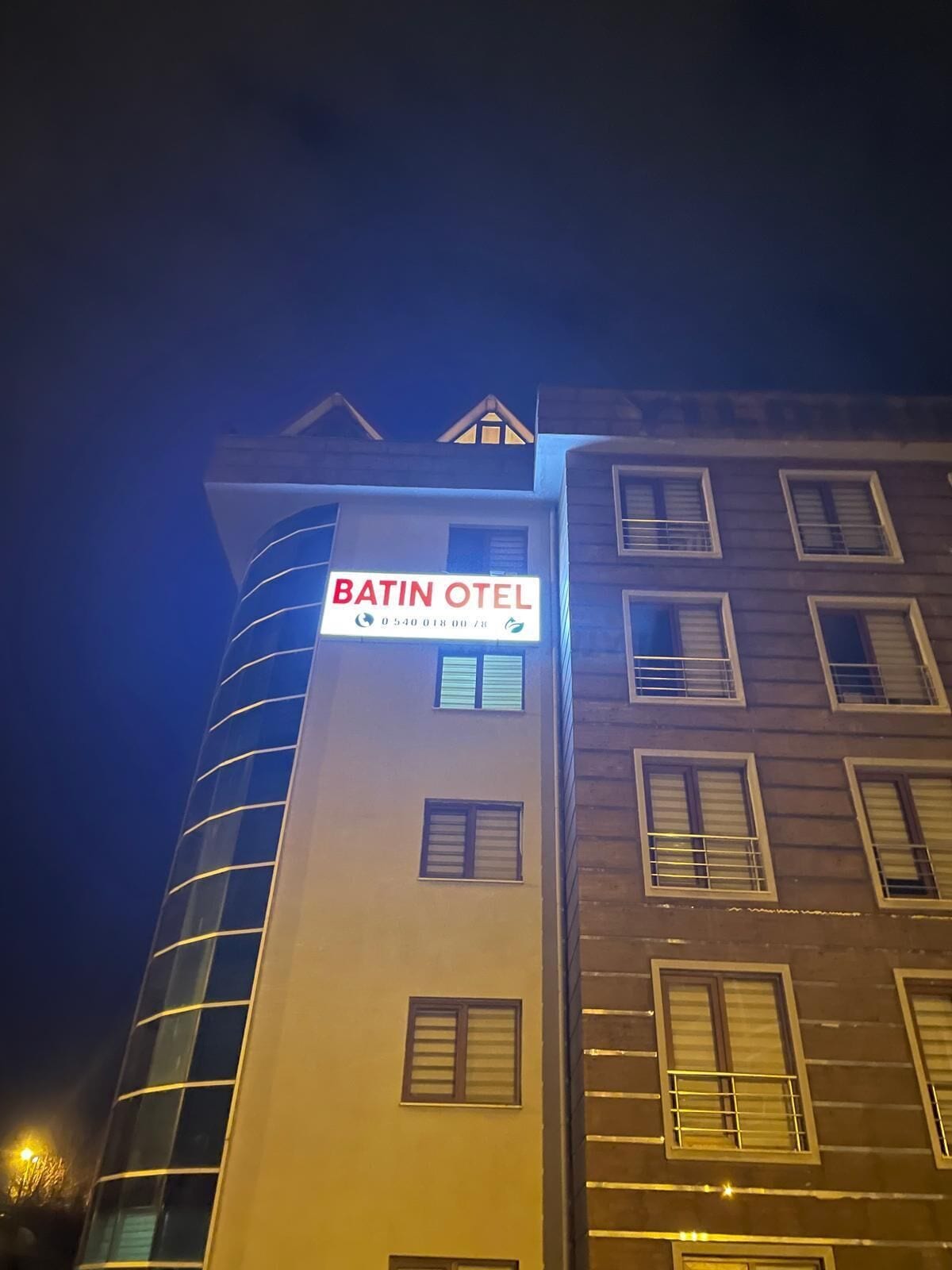 A hotel building with a sign reading 'BATIN OTEL' and a contact number.