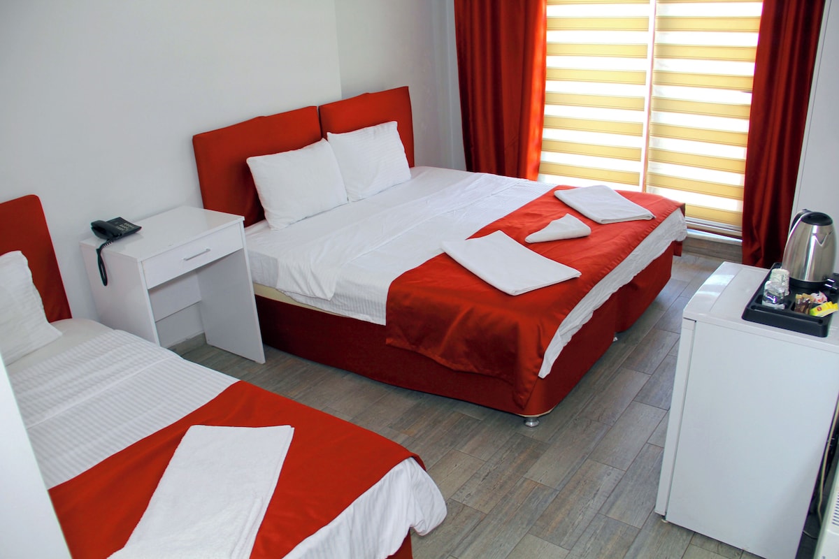 A hotel room with two beds, a desk, and a minibar.