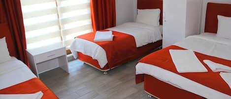 A hotel room with three beds, each with white linens and orange bedding.