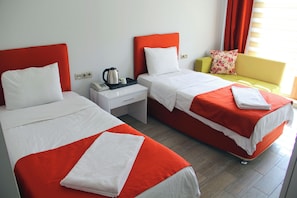 A hotel room with two single beds, a nightstand with a kettle, a telephone, and a small table. - BATIN OTEL (Karabük)