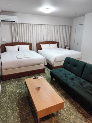 A hotel room with two beds, a green sofa, a wooden coffee table, and a ceiling light. - TOWER HOTEL (FUKUOKASHI/HAKATAKU/REISENMACHI)