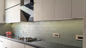 Une cuisine moderne avec des meubles de couleur claire, un plan de travail noir et un revêtement mural vert.