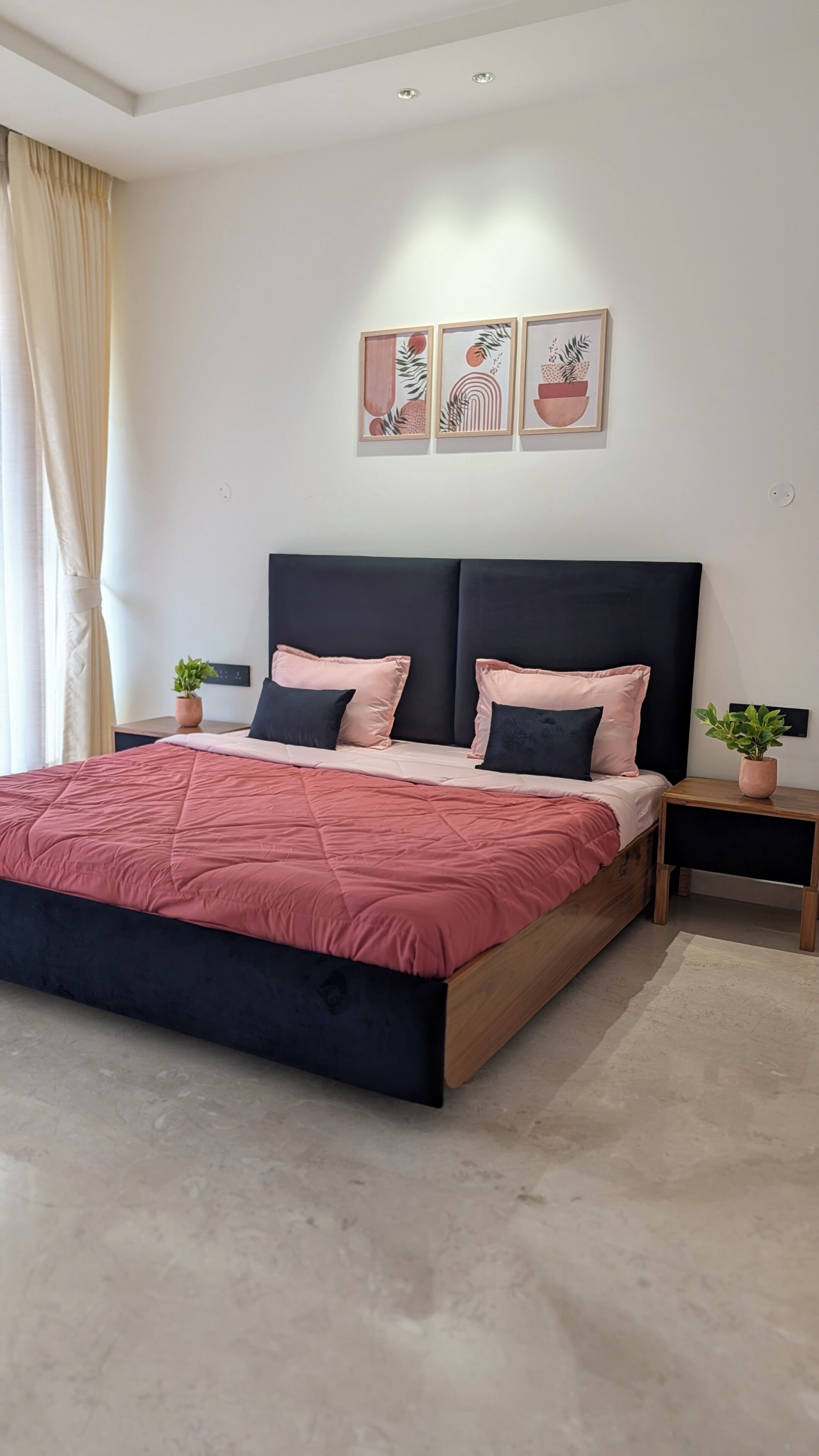 Un dormitorio moderno con una cama grande, dos mesitas de noche y tres obras de arte colgadas en la pared.
